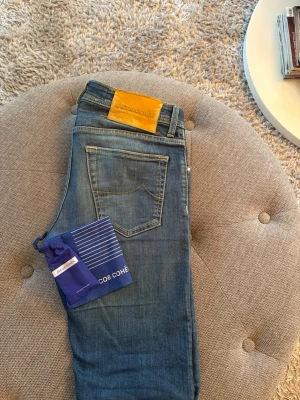Blå jeans från Jacob Cohën - Snygga blå jeans från Jacob Cohën med klassisk femficksdesign och gul patch bak i midjan. Jeansen har en smal passform och är tillverkade i mjukt denimtyg. Perfekta för dig som gillar stilrena och exklusiva jeans. Skick 10/10. Endast seriösa bud. Hör av er vid minsta fråga Mvh Lusso Studio⚜️