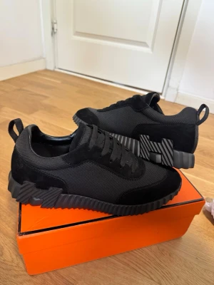 H skor - Snygga svarta H sneakers med chunky, räfflad sula i svart och grått. Ovandelen är i en mix av mocka och textil, med matchande svarta skosnören och dragflikar bak. Diskret H -detalj på sulan för en exklusiv touch.