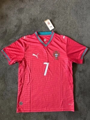 Portugal VM 26/27 hemma Ronaldo 7 - Fotbollströja med Ronaldo på ryggen. Tröjan är helt ny med tagg kvar och i perfekt skick. Perfekt för dig som är supporter, samlar på fotbollströjor eller vill ha en snygg tröja till träning och vardag.                                                                      🔻 Skickas inom 24 timmar.                                         Vid intresse eller frågor är det bara att skicka 👍