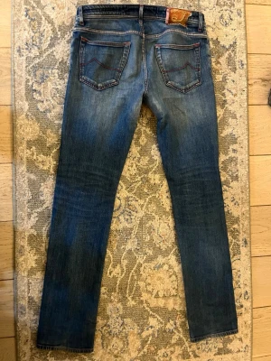 Blå jeans från jacob cohën - Säljer ett par klassiska blå jeans från jacob cohën i storlek 32. Dem är använda och har blivit lagade.