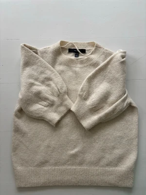 Beige puffärm stickad tröja vero moda - Säljer en beige stickad tröja från vero Moda med trendiga puffärmar och ribbade muddar. Tröjan har rund halsringning och är gjord i mjukt material, perfekt för lager på lager. Enkel men snygg design som passar till det mesta.