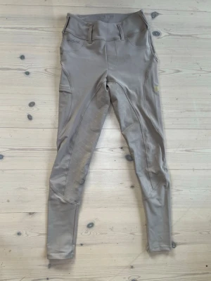 Beige ridleggings från Maya Delorez  - Säljer ett par beige ridleggings med hög midja, mobilficka på sidan och helskoning i silikon för extra grepp. Snygg och sportig design med detaljerade sömmar. Perfekta för dig som gillar stilrena och funktionella ridkläder. Nypris 1500:-