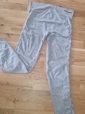 Tränings tights - Snygga grå leggings från Hummel i ett sömlöst material som sitter riktigt skönt. De har hög midja och är perfekta för både träning och chill. Diskret logga vid linningen och stretchigt tyg som formar sig efter kroppen. Storlek L/Xl pga stretch, passat även mej med M