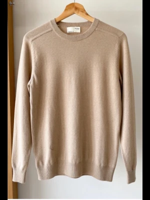 Beige stickad tröja från Selected Homme storlek S - Snygg beige stickad tröja från Selected Homme i storlek S. Tröjan har rund hals och långa ärmar, perfekt för lager-på-lager. Materialet är mjukt och skönt, och den neutrala färgen gör den enkel att matcha med olika outfits.