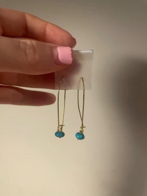 3 nya par örhängen  - Snygga örhängen med lång, tunn guldtonad båge och små turkosa pärlor längst ner. Enkla men ändå unika, perfekta för att ge din look lite extra färg. Materialet ser ut att vara metall och pärlorna är runda och blanka.