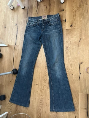 Blå bootcut jeans guess - Säljer ett par blå bootcut jeans från Miss Sixty med snygg tvätt och broderade detaljer på bakfickorna. Klassisk femficksmodell med låg midja och utsvängda ben. Tillverkade i denim med skön stretch för extra komfort.