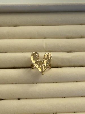 Guldfärgad ring med hjärta - Unik guldfärgad ring med ett stort, hamrat hjärta som dekoration. Hjärtat har en organisk och ojämn yta som ger en cool och trendig känsla. Perfekt för dig som vill sticka ut med dina accessoarer.
