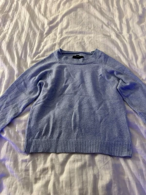 Ljusblå stickad tröja Vero Moda - Ljusblå stickad tröja från Vero Moda med rund halsringning och ribbade muddar vid ärmslut och nederkant.