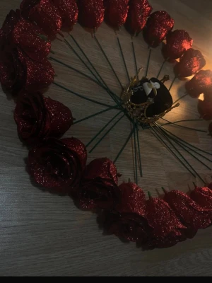 Blomkrona med röda rosor och gulddetaljer - Säljer en hårkrans med glittriga röda rosor och dekorativa guldfärgade fjärilar. Kransen har gröna stjälkar och en liten guldfärgad krona i mitten. Materialet är konstblommor och metall. Perfekt för dig som vill ha något unikt och kreativt i håret.