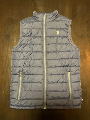 Mörk blå dunväst från U.S. Polo Assn. - Säljer en snygg och lätt  väst i mycket fint skick. Endast använd 3–4 gånger.  • Mörkblå färg • Lätt  – perfekt för vår/höst • Två fickor inne och utan på jackan. • Stilren design som passar till allt • Bekväm passform  Perfekt att bära över hoodie eller tröja när det är lite kyligare ute.  💰 Pris: 500 kr  Nästan som ny – inga skador eller slitage.  Skickas snabbt vid köp‼️🚚. Hör av dig vid intresse!       - Jag är 170-172 cm och den passar 