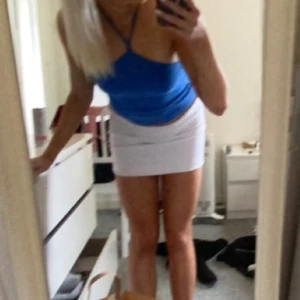 Blå halterneck topp - Säljer en vit minikjol med rak passform och enkel, stilren look. Kjolen är kort och har en clean vibe som passar till många olika toppar. Perfekt för dig som gillar minimalistisk stil.