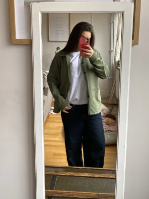 Grön overshirt med fickor - Stilren grön overshirt i bomull med klassisk krage och knäppning framtill. Två stora utanpåfickor och en mindre bröstficka ger en avslappnad look. Perfekt att slänga över en t-shirt för en casual vibe. Helt ny, använder inte den pga storlek, nypris 2500kr 