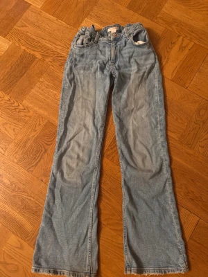 Blå bootcut jeans från Gina Tricot - Säljer ett par ljusblå bootcut jeans från Gina Tricot i storlek 158. Jeansen har klassisk femficksmodell, normalhög midja och utsvängda ben. Perfekta för en avslappnad och trendig look.