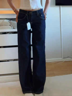 Mörkblå wide leg jeans - Säljer ett par mörkblå jeans med wide leg passform och hög midja. Jeansen har klassiska fem fickor, kontrastsömmar och raka ben. Perfekta för dig som gillar en avslappnad och trendig stil. Från subdued, Stl 38 men sitter mer som 32/34! Endast testade. Köpta för 800💕