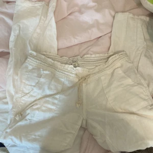 Linnebyxor Roxy  - Snygga vita linnebyxor från Roxy i linne med avslappnad passform. De har elastisk midja med snörning, två fickor fram och två bak. Perfekta för varma dagar och chill vibes. Klassisk och enkel stil som funkar till det mesta. Köpte för 600 använda fåtal gånger. 