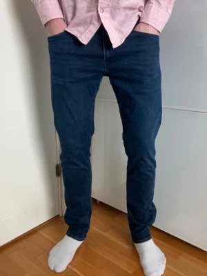 Blå jeans från Replay - Snygga blå jeans från Replay med klassisk femficksdesign och raka ben. Jeansen har en tydlig logotyp-patch bak i midjan och är tillverkade i ett mjukt denimtyg som ger en bekväm känsla. Perfekta för en avslappnad och trendig stil.