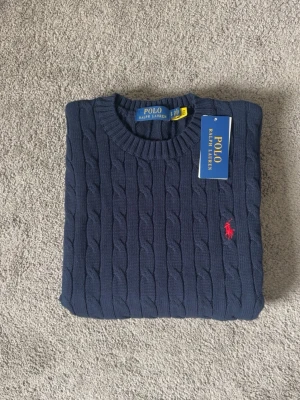 Mörkblå kabelstickad tröja Polo Ralph Lauren - Kabelstickad mörkblå tröja från Polo Ralph Lauren. Endast testad, storlek S. Perfekt för mildare väder vid frågor eller funderingar tveka inte på att höra av dig mvh 47 😁