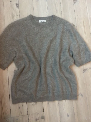 Beige stickad tröja Soft Goat - Mysig beige stickad tröja från Soft Goat med korta ärmar och rund hals. Tillverkad i fluffigt material som ger en lyxig känsla. Perfekt för lager på lager och enkel att styla till olika outfits.