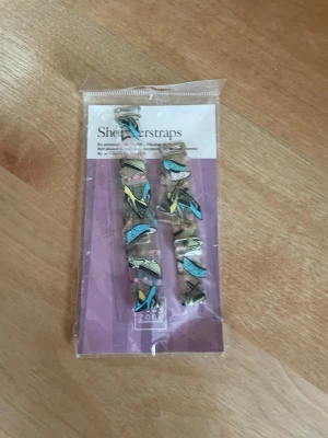 Transparenta axelband till BH - Säljer ett par transparenta axelband till BH, perfekta när du vill ha axelbandslöst utseende men ändå stöd. Axelbanden är justerbara och har dekorativa detaljer i flera färger som blått, gult och svart. Passar de flesta bhar med avtagbara axelband.
