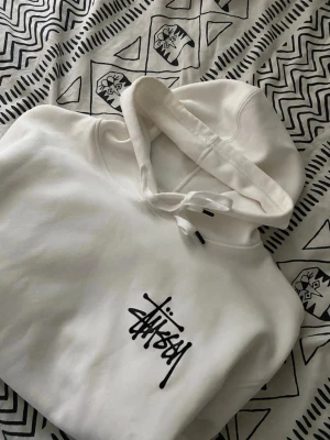 Vit Stussy hoodie-storlek M - Vit Stüssy hoodie i storlek L (passar som M). Använd väldigt lite, inga fläckar eller skador – i princip nyskick. Sjukt snygg hoodie som passar nästan alla stillar. Pris är inte hugget i sten.