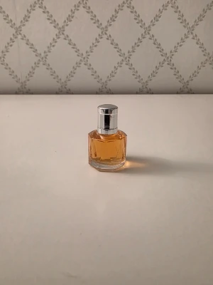 Aigner Private Number EdT miniatyr - Säljer en miniatyrflaska av Aigner Private Number 5ml  Eau de Toilette. Flaskan är åttakantig i genomskinligt glas med silverfärgat lock och innehåller en bärnstensfärgad parfym. Perfekt för dig som gillar exklusiva och klassiska dofter.