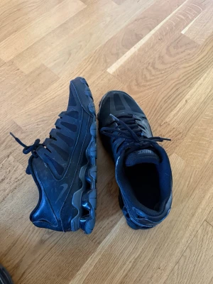 Nike air Max skor  - Snygga svarta Nike sneakers med cool design och tydliga detaljer i både mesh och läder. Skorna har en chunky sula och klassisk snörning. Perfekta för dig som gillar sportig stil och vill ha något som sticker ut lite extra.