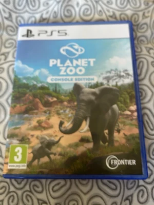 Planet Zoo Console Edition PS5 - Planet Zoo Console Edition till PS5 är ett djurparksbyggarspel där du skapar och hanterar din egen zoo-värld. Omslaget är blått med illustration av elefanter och savannmiljö. Spelet är i Ultra HD och har stöd för en spelare. Perfekt för dig som gillar strategi och djur.