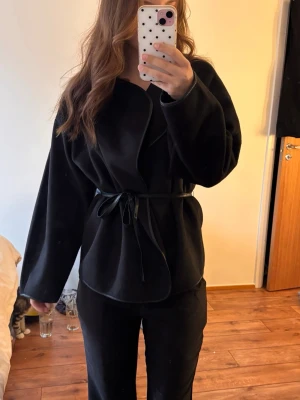 Svart omlottkappa med skärp - Svart omlott kappa med knytband i midjan! Storlek S och bara testad på! Super fin! Köpt nypris för 799