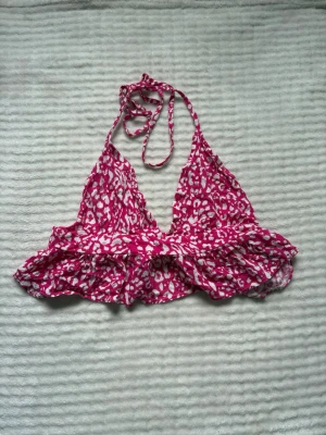 Rosa leopardmönstrad topp - Supersöt topp i rosa och vitt med leopardmönster. Modellen har volangkant nedtill, knyt i nacken och omlottkänsla framtill. Perfekt för sommarens strandhäng eller poolparty. Aldrig använd alls!💓🌸