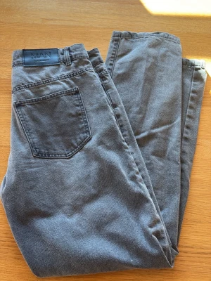 Grå jeans från BoohooMAN - Säljer ett par grå jeans från BoohooMAN med klassisk femficksmodell och rak passform. Jeansen har en snygg tvättad look och är tillverkade i mjukt denimtyg. Perfekta för en avslappnad och trendig stil.