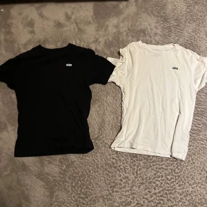 T-shirtpaket från Champion, Vans & Nike - Säljer sex t-shirts: en svart och en vit från VÄRE med liten logga på bröstet, en vit Vans med stor logga på ryggen och en vit Nike Air med stor logga och röd swoosh framtill. En brun Nike och en svart Champion.Alla har klassisk passform och är kortärmade. Perfekta basplagg för en avslappnad stil. Alla säljs tillsammans. Alla har ungefär samma storlek och passform.