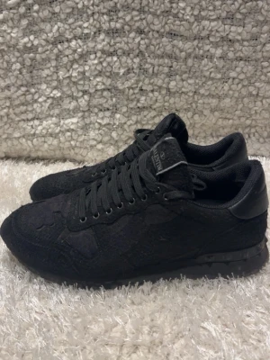 Svarta valentino rockrunners - Säljer ett par svarta sneakers från Valentino med cool textil- och mockayta. Skorna har svarta snören, svarta detaljer i läder och en chunky sula med nitar på hälen. Perfekta för dig som vill ha en stilren men edgy look. Självklart äkta! Dom är storlek 41 men passar även 42. Skriv vid minsta fundering! 