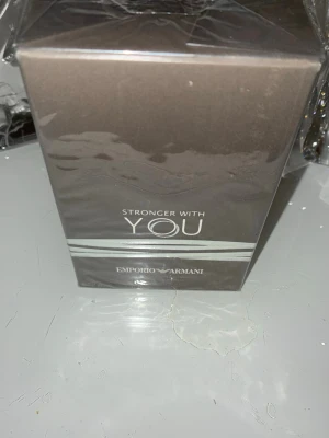 Emporio Armani Stronger With You parfym - Emporio Armani Stronger With You är en parfym i en elegant, mörkgrå kartong med silverdetaljer. Förpackningen har en stilren och modern design som känns lyxig och trendig. Perfekt för dig som gillar exklusiva dofter och vill ha något från ett välkänt märke.