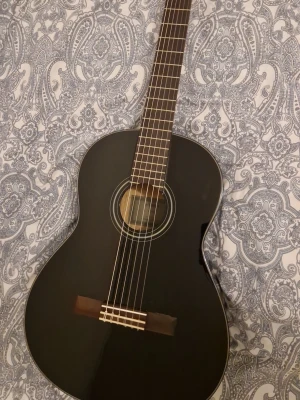 Yamaha c40 klassisk akustisk gitarr - Säljer en svart klassisk akustisk gitarr med sex strängar och trägreppbräda. Gitarren har en snygg, blank finish och traditionell form. Inga repor,skador etc.Perfekt för dig som vill börja spela eller bara vill ha ett stilrent instrument hemma.(går att ändra pris)
