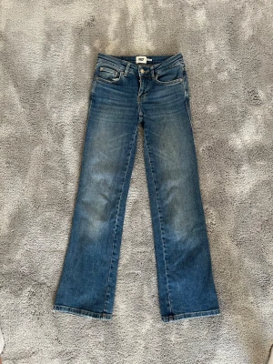 Blå bootcut jeans från lager 157 - Snygga blå bootcut jeans från lager 157 med klassisk femficksdesign och knappstängning. Jeansen har lätt slitna detaljer framtill och bakfickor med lock och knappar. Tillverkade i denim med en skön passform och utsvängda ben.