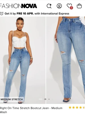 Bootcut jeans från Fashion Nova - Snygga bootcut jeans i mellanblå tvätt från Fashion Nova. Jeansen har hög midja, slitningar på låren och knäna samt klassiska fem fickor. Materialet är stretchigt för en bekväm passform och de har dragkedja och knapp framtill.