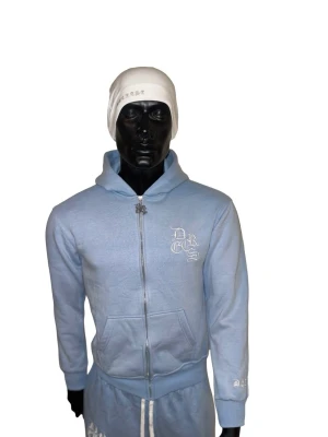 Decrese Sweden Hoodie i Ljusblått - Stilren ljusblå hoodie i unisexmodell med vit broderad logga, svarta detaljer och drake på huvan. Mjuk bomull med stretch och stentvättad finish för modern streetwear-look. Oversize känsla. Mått (XS): Axel 46, bröst 46, längd 59, ärm 50. Två fickor. Obs: Köpare står för returfrakt. Mått kan variera 1–3 cm.