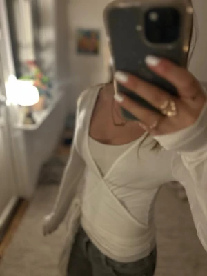 Vit omlottopp med lång ärm - Säljer snygg vit omlottopp med lång ärm och v-ringning. 