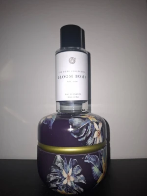 Bloom Bomb Eau de Parfum 45 ml - Fräsch parfym från The Dupe Collection, Bloom Bomb No. 014. Flaskan är genomskinlig med svart lock och stilren vit etikett. Innehåller ca 45 ml Eau de Parfum. Perfekt att ha i väskan eller på sminkbordet. Snygg och modern design.