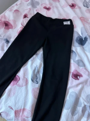 Svarta fleecefodrade leggings - Mysiga svarta leggings med mjukt fleecefoder på insidan som håller dig varm under kalla dagar. De har en klassisk, tight passform och är perfekta för att kombinera med oversized tröjor eller hoodies. Materialet är stretchigt och bekvämt.