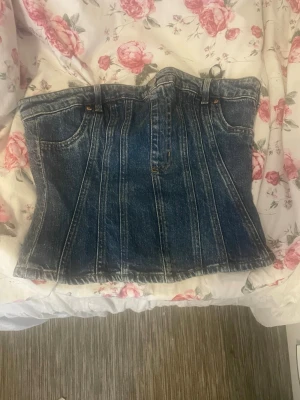 Jeanskorsett från H&M Divided - Trendig jeanskorsett från H&M Divided i tvättad blå denim. Snygga sömmar och fickdetaljer framtill ger en cool och edgy look. Perfekt att styla med både kjol och byxor för en statement-outfit. Materialet är klassisk bomullsdenim.