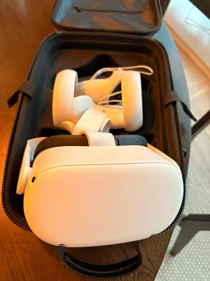 Oculus Quest 2 VR-headset med kontroller - Säljer ett Oculus Quest 2 VR-headset i vit färg med matchande handkontroller och tillhörande bärväska. Headsetet har justerbara remmar och ergonomisk design för maximal komfort. Perfekt för gaming och VR-upplevelser hemma.