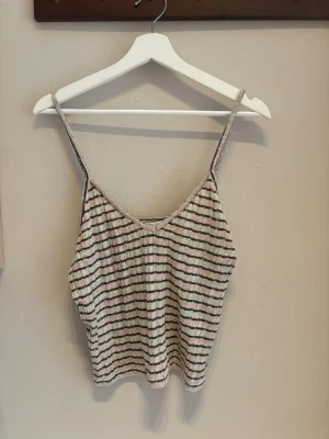 Randig linnetopp från Zara - Säljer en söt randig linnetopp från Zara i ljusa toner av rosa, beige och svart. Toppen har smala axelband, v-ringning och är ribbad i materialet. Perfekt för varma dagar och enkel att styla med jeans eller kjol. Det av populärt set