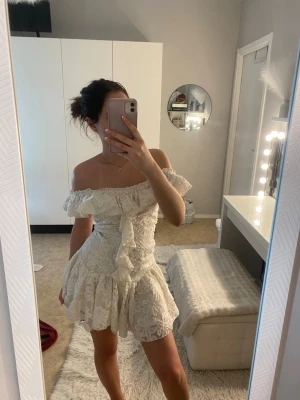 Vit offshoulder klänning Missguided - Supersöt vit kortklänning från Missguided med offshoulder och volangdetaljer. Klänningen har ett blommigt mönster, omlottkänsla framtill och markerad midja. Perfekt för sommarens alla tillfällen! Så fin till studenten!!!