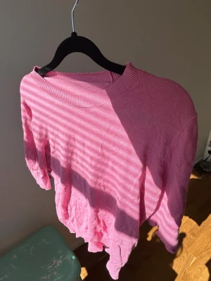 Rosa stickad tröja med rund hals - Säljer en rosa stickad tröja med rund halsringning och avslappnad passform. Tröjan har långa ärmar och ribbade muddar vid halsen. Perfekt för dig som gillar färg och vill ha något mjukt och bekvämt i garderoben💗🥂