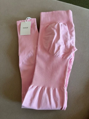 Rosa seamless leggings från thrivin - Rosa träningstights med ribbad struktur och hög midja. Tightsen har en scrunch-detalj baktill som framhäver formerna. Oanvända, bara testade. 