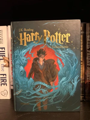 Harry Potter och Dödsrelikerna - Svensk utgåva av 'Harry Potter och Dödsrelikerna' med ett färgstarkt omslag i blått och rött. Boken har hårda pärmar och guldfärgad text på framsidan. Omslaget pryds av en illustrerad Harry Potter omgiven av magiska effekter.