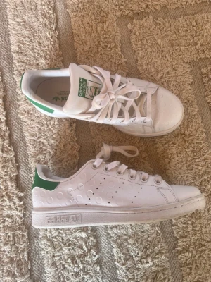 Adidas Stan Smith vit/gröna sneakers - Klassiska vita Adidas Stan Smith sneakers med gröna detaljer på hälen och tungan. Använda ca 3 gånger. Storleke 37 1/3 