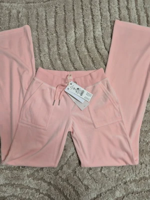 Supersköna ljusrosa mjukisbyxor i velour xs - Säljer ett par ljusrosa mjukisbyxor från Gima Tricot i mjuk velour. Byxorna är i bootcut med resår i midjan som kan justeras med dragsko och stora fickor framtill. Perfekta  nu till sommaren och supergulliga med en vit topp. Pris kan diskuteras. 