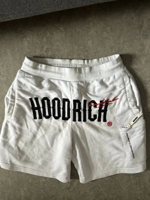 Vita Hoodrich shorts - Vita Hoodrich shorts perfekt för sommaren då den modellen inte säljs längre i butik. Shortsen är svåra att få tag på,  för ett sånt bra pris jag erbjuder. OBS Shortsen är 100% äkta köpt från JD sports. Storleken är S men XS och M passar lika bra. Shortsen är i mycket bra skikt då jag anvnänt den några gånger.